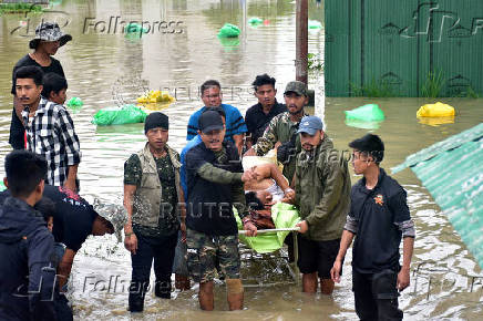 People carry a patient on a stretcher as they wait for a rescue boat to evacuate him from the flood-affected Jawaharlal Nehru Institute of Medical Sciences hospital, following heavy rains in Imphal East