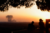 Smoke rises from Gaza after an explosion, as people look towards Gaza from a viewpoint in Israel