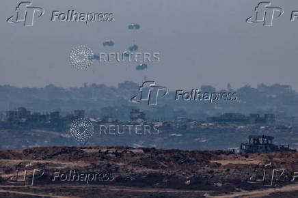 An aircraft drops humanitarian aid packages over the Gaza Strip, as seen from Israel