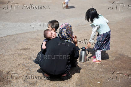 An Afghan woman, who was deported from Iran, sits with her children at a camp for returning migrants near the Islam Qala border crossing