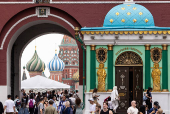People walk by Voskresenskie Gates with Saint Basil?s Cathedral and Red Square seen in the background, in Moscow