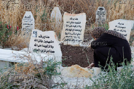 Palestinians visit graves of their relatives at a cemetery in Jenin camp