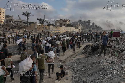 Displaced Palestinians carry relief parcels along Rashid Street, west of Gaza City