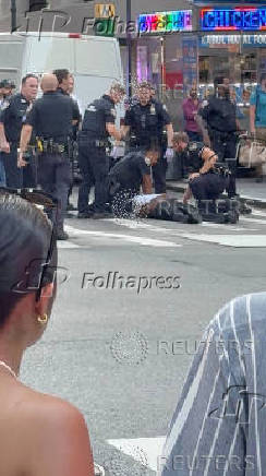 Police officers try to rescue an injured man next to a Midtown Manhattan skyscraper, in New York