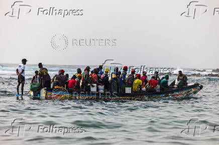 Fishermen sit in their pirogue as they set out to sea from the fishing quay, in Dakar