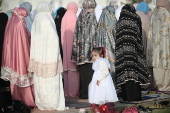A girl looks on as Indonesian Muslim women offer Eid al-Adha prayers at Baiturrahman mosque in Banda Aceh