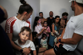 People take shelter opposite to the Meditarenean beach as siren sounds following missile attack from Iran on Israel, in Tel Aviv
