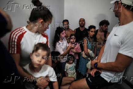 People take shelter opposite to the Meditarenean beach as siren sounds following missile attack from Iran on Israel, in Tel Aviv