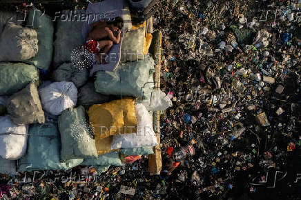A drone view shows a boy sleeping on sacks of garbage along the polluted Pasig River on World Environment Day in Manila