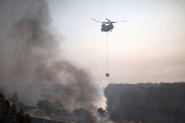 A firefighting helicopter drops water to extinguish fire at the area of Souni near Limassol,
