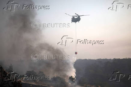 A firefighting helicopter drops water to extinguish fire at the area of Souni near Limassol,