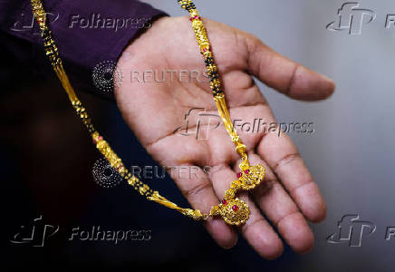 A goldsmith holds a chain inside a jewellery making workshop in Mumbai