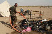 A soldier extinguishes a fire following a drone attack in Ad-Damar