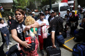 Migrants gather outside the Venezuelan embasssy waiting for a flight back to their country
