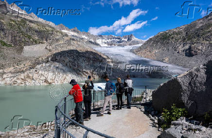Tourists look at the Rhone glacier and its lake amid climate change in Obergoms