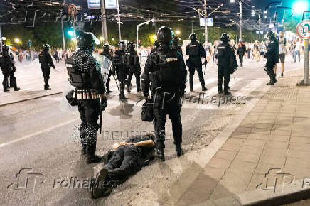 Serbian police stand next to a detained protester during standoff between ruling party supporters and anti-government protesters in Belgrade