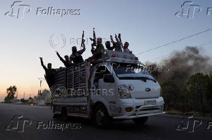 Bedouin fighters ride on a vehicle along a street, at Sweida governorate