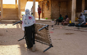 A woman carries a bed base as she leaves the camp following a drone strike, in Ad-Damar