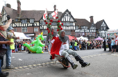 Competitors participate in the Pinner Wheelbarrow Race as part of a St. George's Day celebration, in London