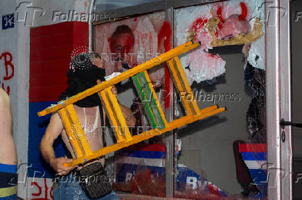 A demonstrator breaks a window during a standoff between ruling party supporters and anti-government protesters in Novi Sad