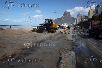 A bulldozer clears sand on the shore of Leblon beach after big waves hit Rio de Janeiro