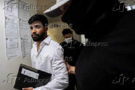 A migrant is detained by federal immigration officers at U.S. immigration court in Manhattan