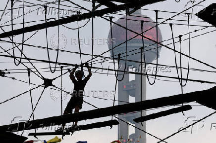 A person crosses a wire bridge at an athletic playground in Shanghai