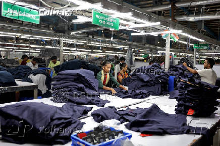 Workers pack shirts and hoodies after final inspection in a garment manufacturing unit on the outskirts of Ahmedabad
