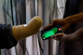 Technician uses a mobile phone for 3D scan of a patient before develping a prosthetic limb at the Bioniks Private Limited, in Karachi
