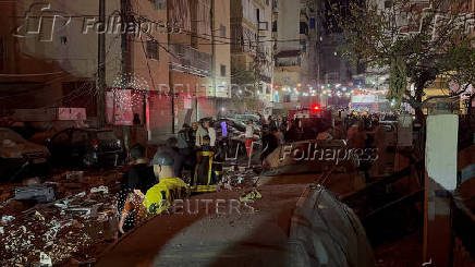 People gather near a building where a floor caught fire following an Israeli strike, in which the Israeli military said, it killed Hamas commander Hassan Farhat, in Sidon