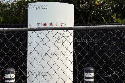 FILE PHOTO: A Tesla electric vehicle charging station sits behind a fence in a parking lot in New Hyde Park, New York