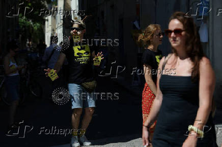 An artist distributes leaflets for a play in a street during the Avignon Festival in Avignon