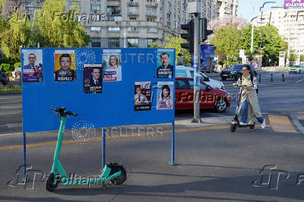 A woman rides a scooter near electoral posters in Bucharest