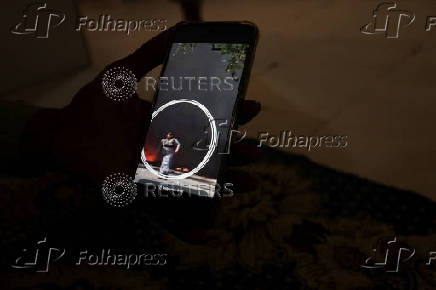 Suresh Patni displays a video of his wife Sita Patni on a smart phone, who was injured in an Air India Boeing 787-8 Dreamliner plane crashed during takeoff from an airport, in Ahmedabad