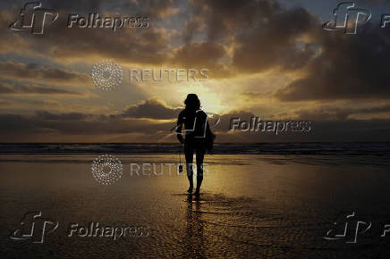 FILE PHOTO: A female surfer walks out into the waves at Cardiff State Beach in Encinitas, California