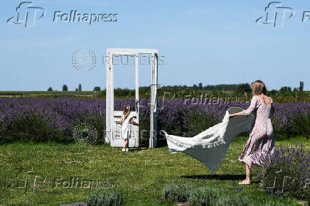 People walk next to a door standing in front of a lavender field in the summer season, in Nowy Pozog