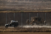 An Israeli military vehicle and D9 bulldozer operate on the Israeli side of the Israel-Gaza border