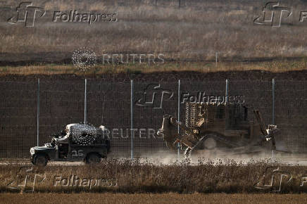An Israeli military vehicle and D9 bulldozer operate on the Israeli side of the Israel-Gaza border