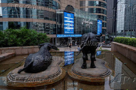 FILE PHOTO: Bull statues are placed in font of screens showing the Hang Seng stock index and stock prices outside Exchange Square, in Hong Kong