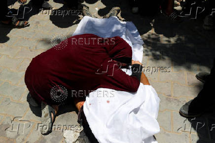 A woman mourns over the body of a Palestinian, who was killed by Israeli fire while seeking aid in northern Gaza, according to medics, at Al-Shifa Hospital in Gaza City