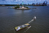Drone view shows a grass covered barge with painting by Franco-Swiss artist Saype entitled ?Address Hate? towed past Statue of Liberty in New York Harbor
