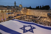 People hold a giant Israeli flag by the Western Wall, in Jerusalem's Old City