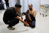 A wounded Palestinian man sits on the floor at Nasser Hospital following an Israeli strike, in Khan Younis