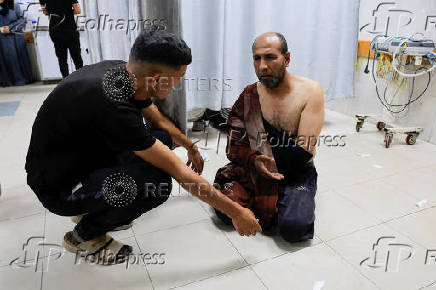 A wounded Palestinian man sits on the floor at Nasser Hospital following an Israeli strike, in Khan Younis