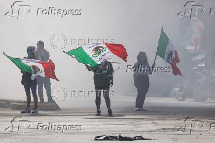 Protesters are blanketed in smoke along Alondra Boulevard during a standoff with law enforcement in Paramount
