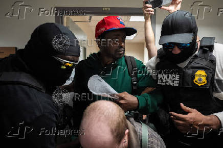 A migrant is detained by federal immigration officers at U.S. immigration court
