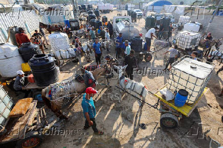 Palestinians collect water amid shortages, at a distribution point in Deir al-Balah in the central Gaza Strip