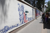 People walk past an anti-U.S. mural on a street in Tehran
