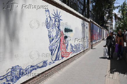 People walk past an anti-U.S. mural on a street in Tehran