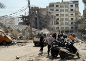 People walk at a damaged site in the aftermath of Israeli strikes, at Beirut's southern suburbs